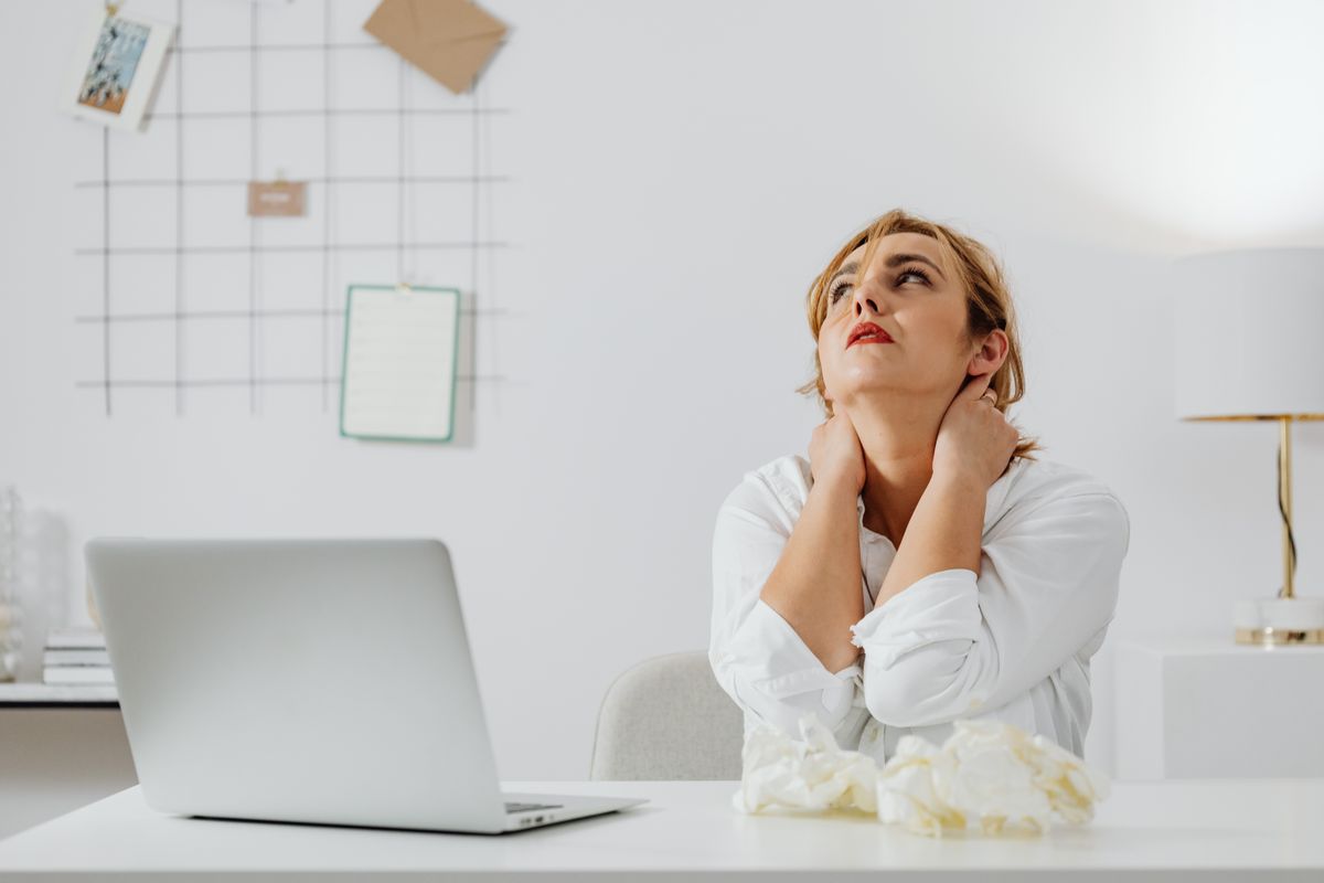 Person experiencing neck and shoulder tension from desk work