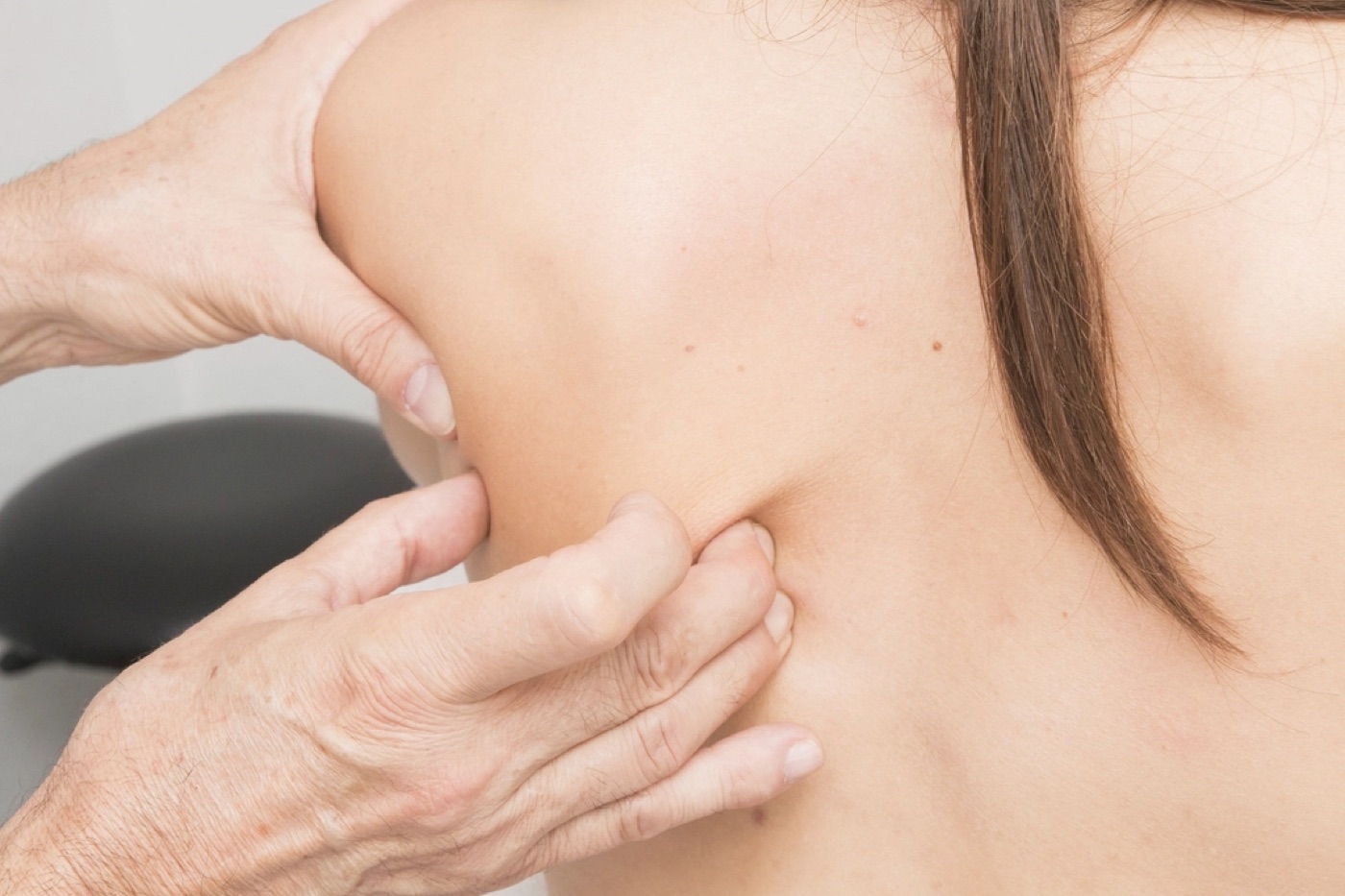 Therapist performing massage on a client's upper back